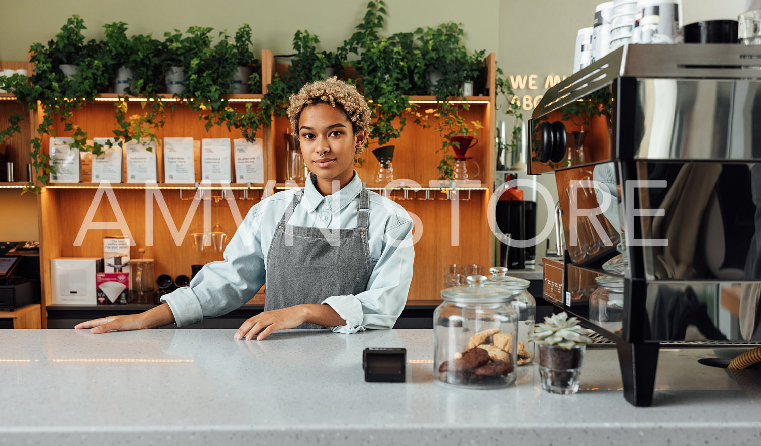 Barista at counter with a coffee machine. Woman in an apron standing in coffee shop.