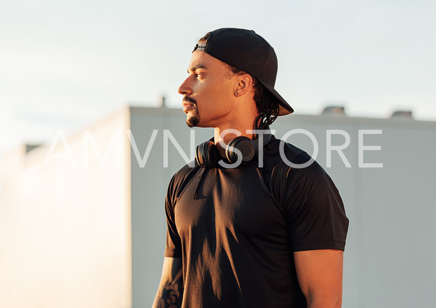 Young male athlete in cap relaxing during outdoor exercises