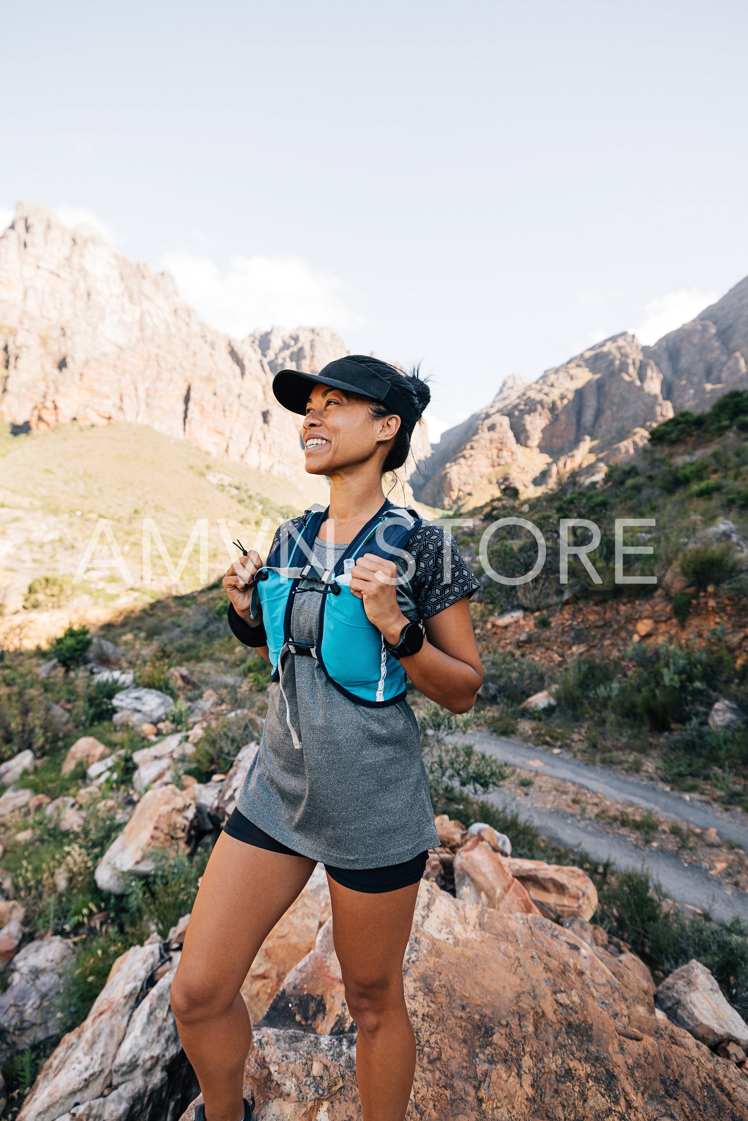 Smiling woman hiker standing in valley looking for path