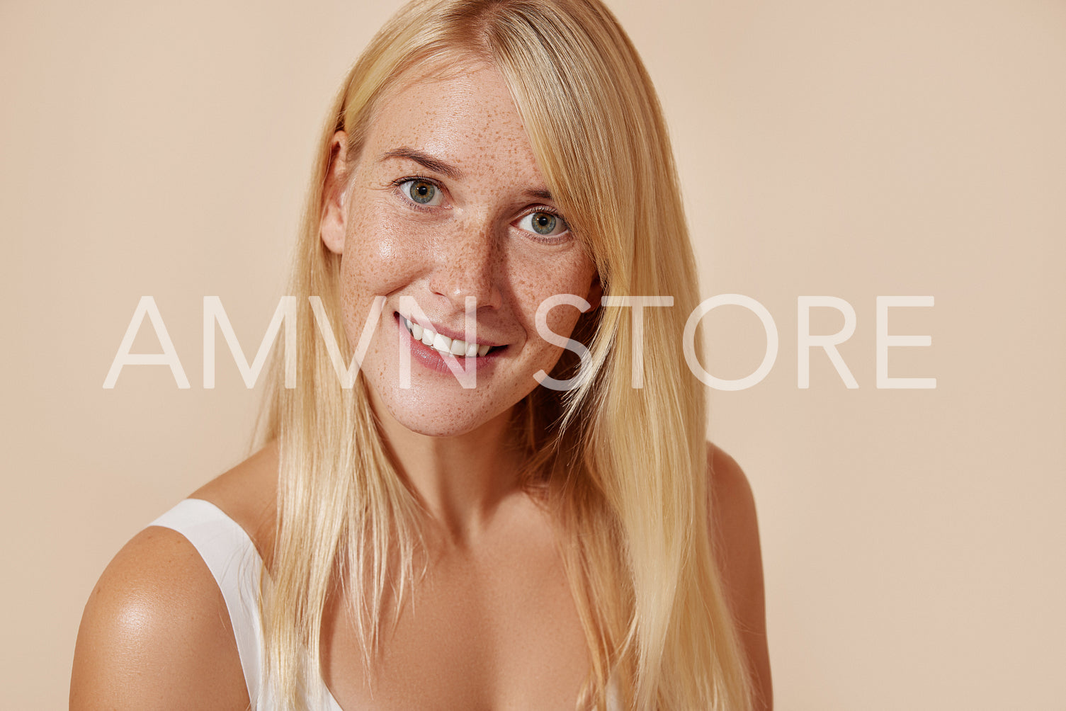 Beautiful young female with smooth freckled skin. Woman with blond hair and perfect skin against a pastel background.