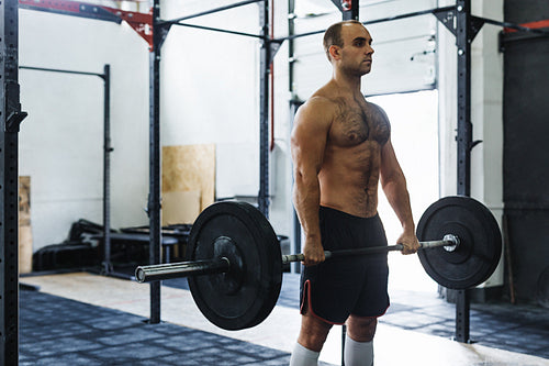 Strong young man exercising with heavy weights at gym