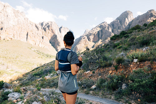 Rear view of sports woman looking at abandoned road in valley