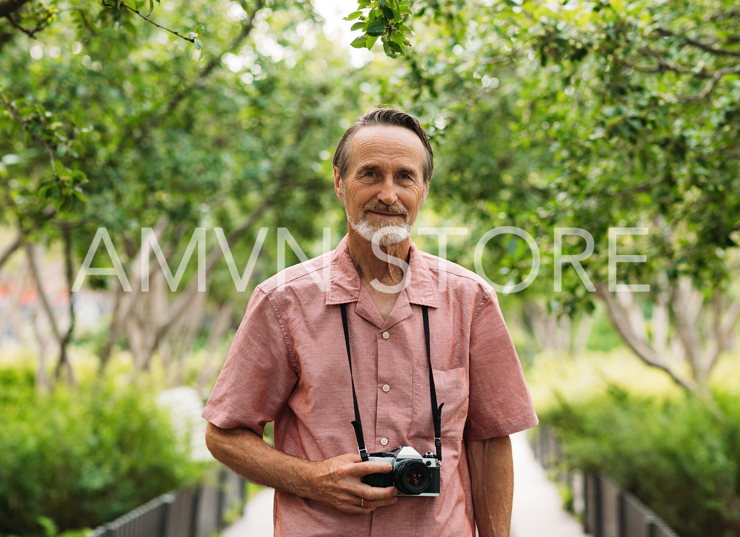 Portrait of an aged male tourist with a film camera in the park