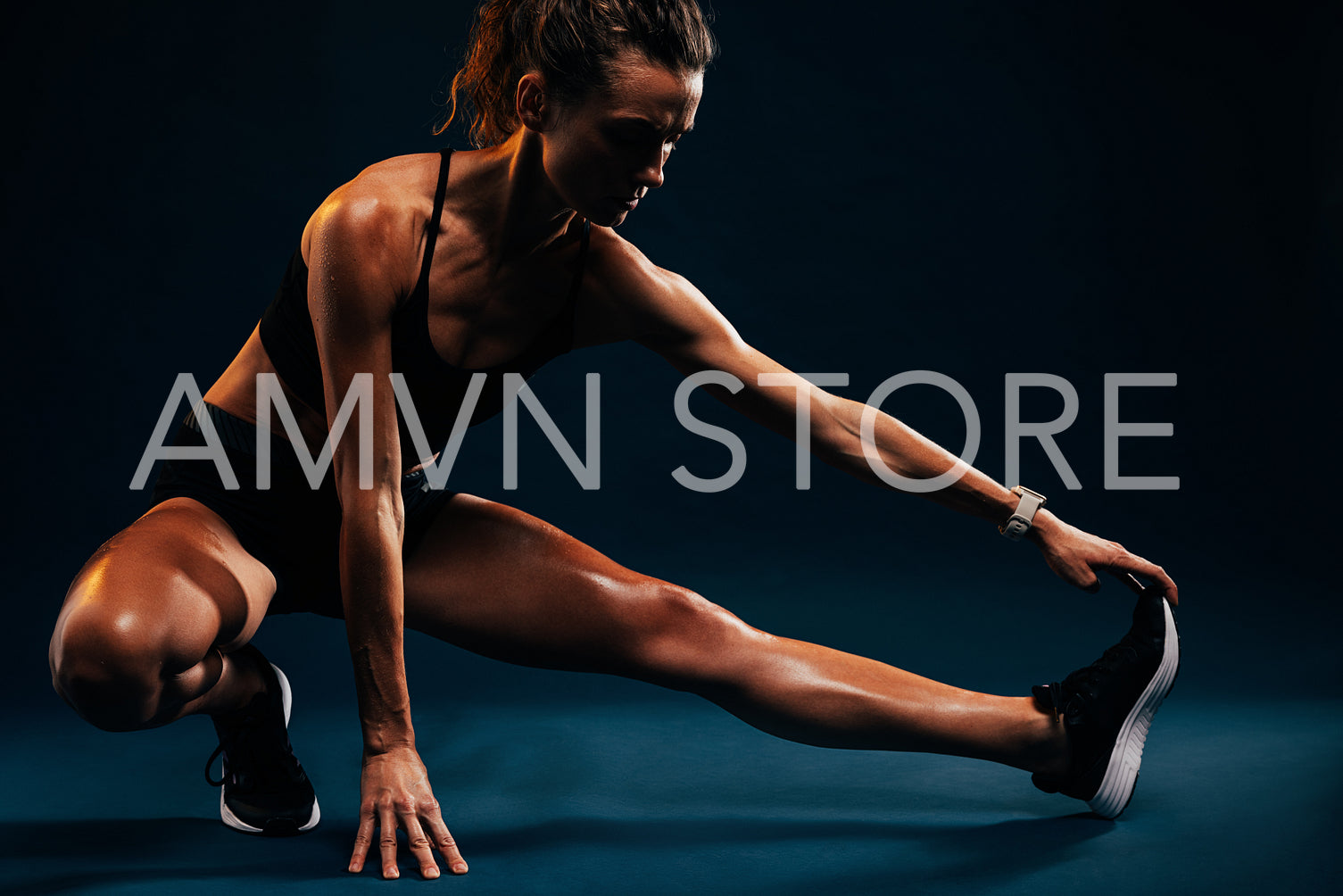 Athlete doing stretching exercises on black background. Female runner stretching leg muscles by touching his shoes while sitting in studio.