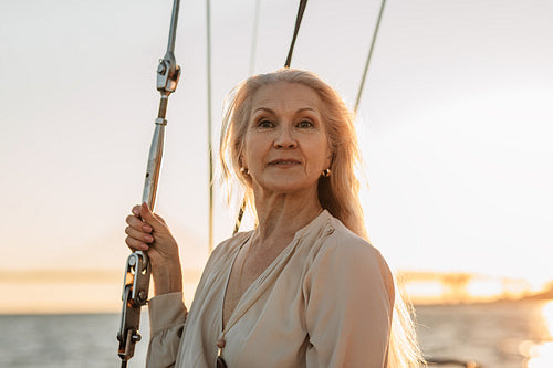 Portrait of stylish mature woman standing on yacht in casuals and looking away