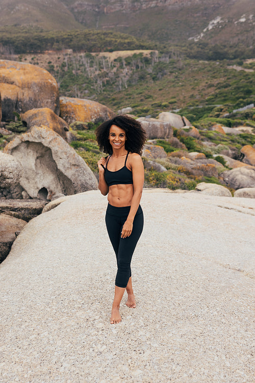 Fit woman in sportswear standing outdoors after yoga training ho