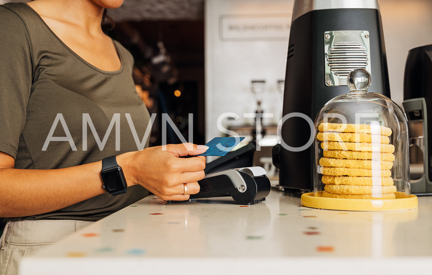 Side view of an unrecognizable woman paying with NFC technology on credit card in cafe