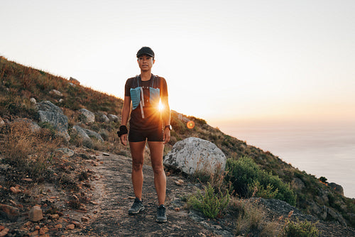 Female in sportswear taking break after trail run training at sunset