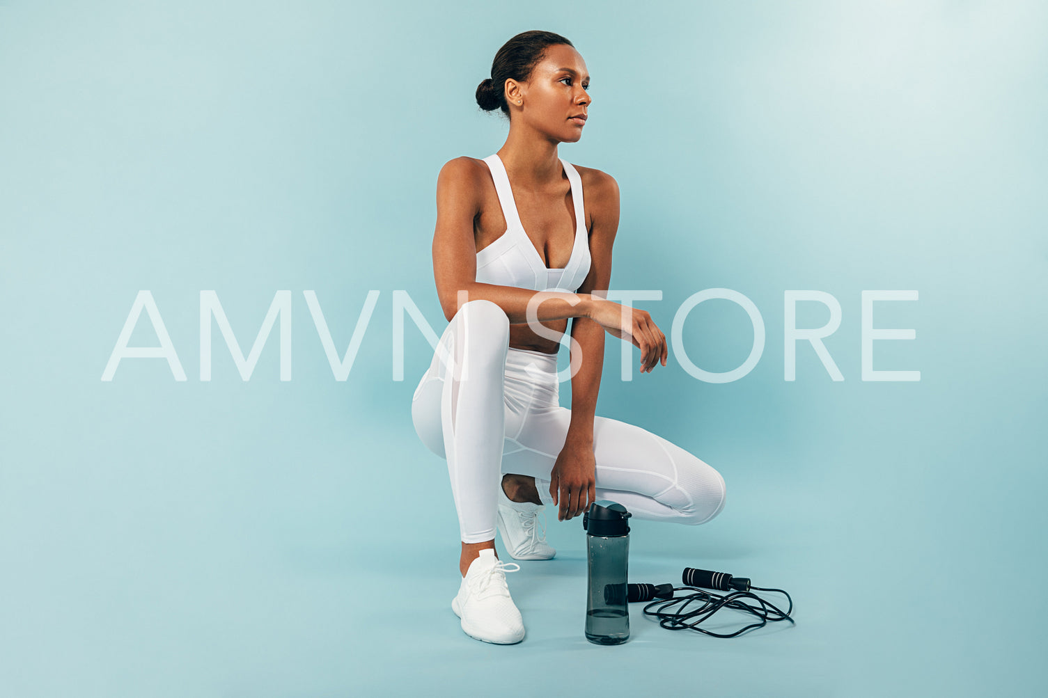 Woman in white sport clothes sitting at a blue background and looking away	