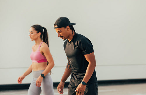 Two athletes preparing to run outdoors. Man and woman relaxing before sprint.