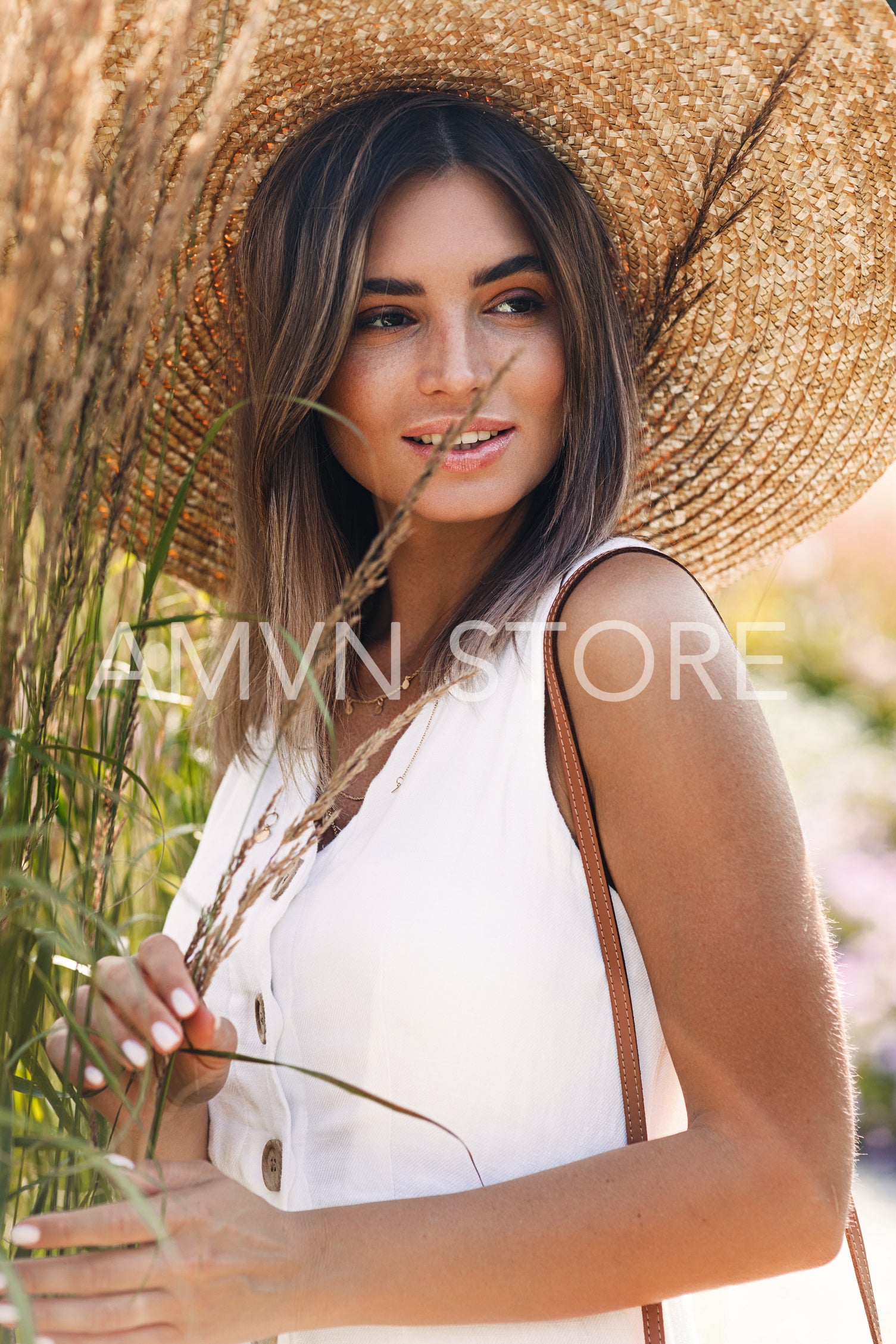 Portrait of a stylish caucasian woman wearing a straw hat standing in a park	