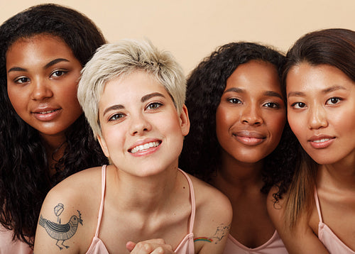 Group portrait of four diverse women in the studio. Female with different skin colors sitting together.