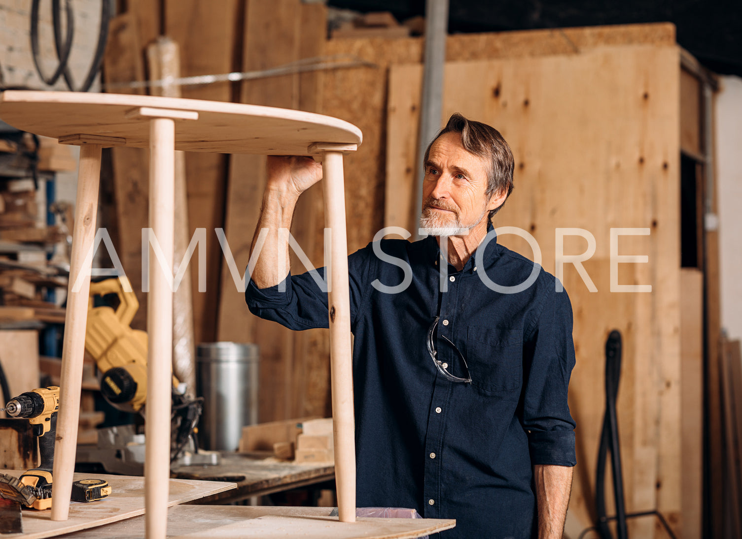 Senior carpenter standing at workbench and looks at the table he made	