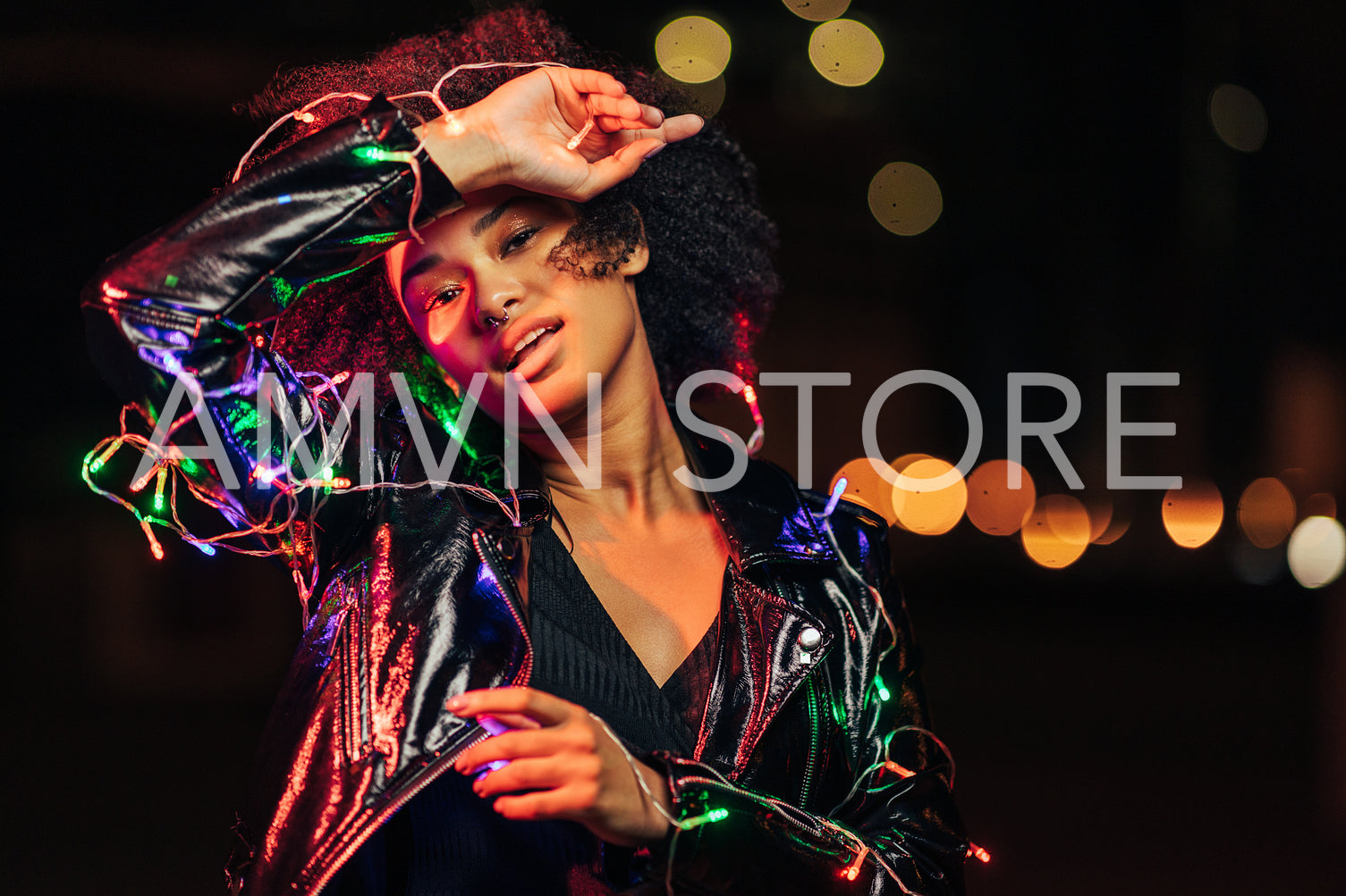 Portrait of a beautiful young woman with christmas lights looking at camera	