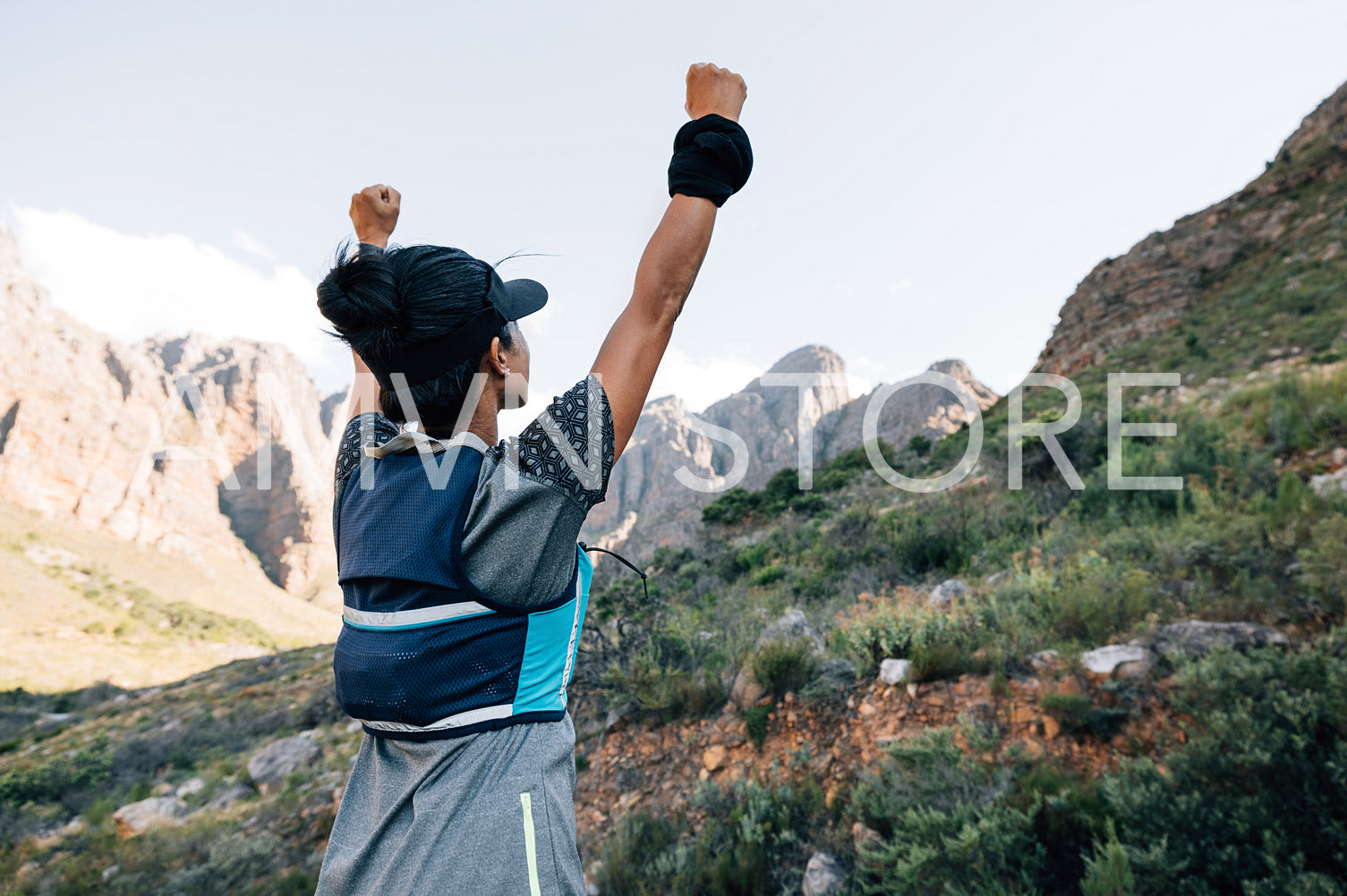 Woman standing in valley looking at mountain with raised hands