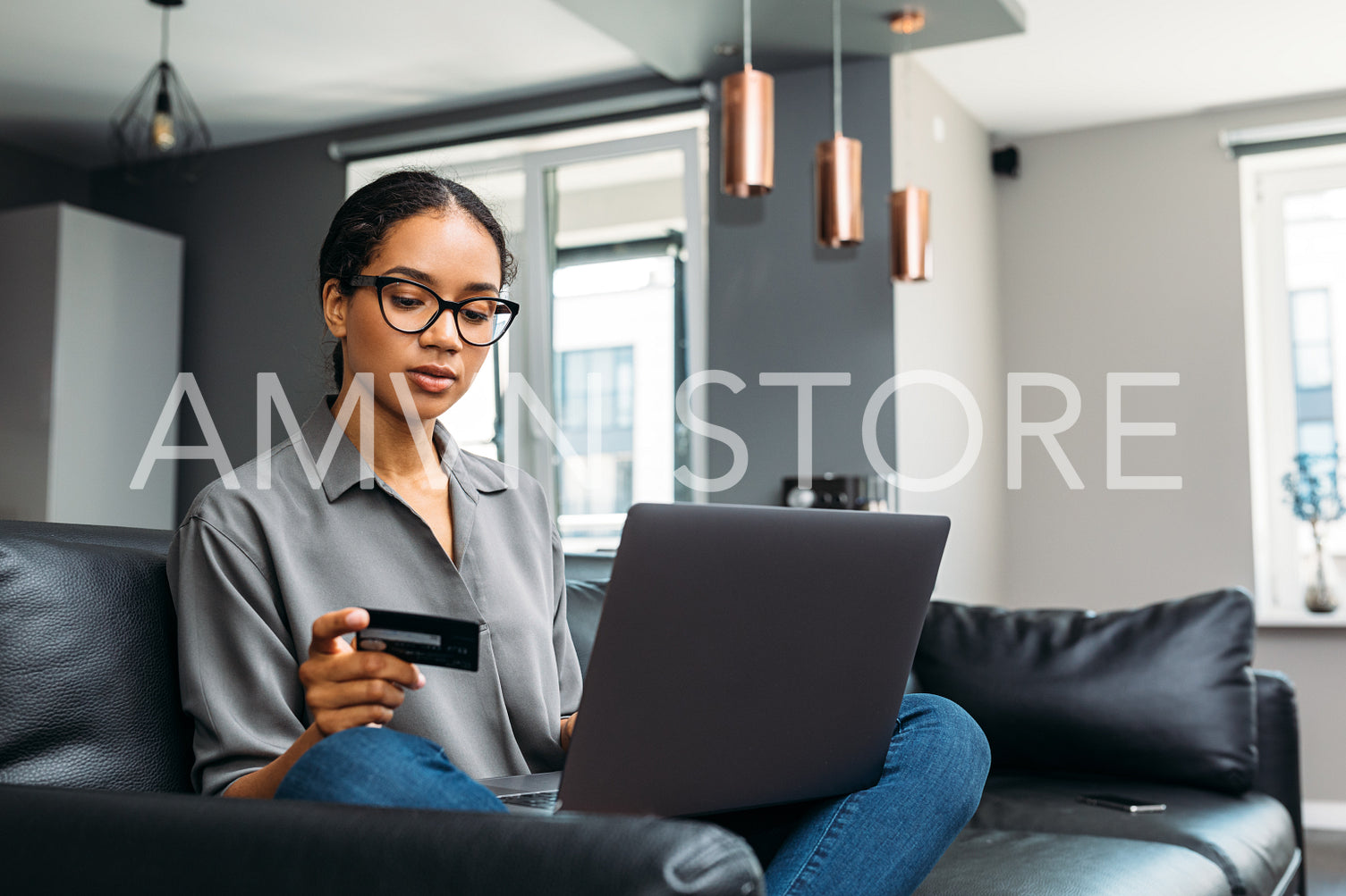 Woman with credit card using laptop in living room. Young female paying online.	