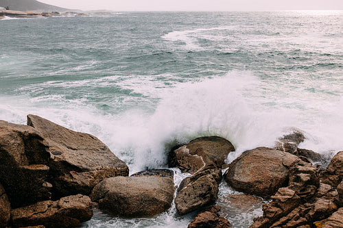 Ocean coast with rocks and big waves at sunset