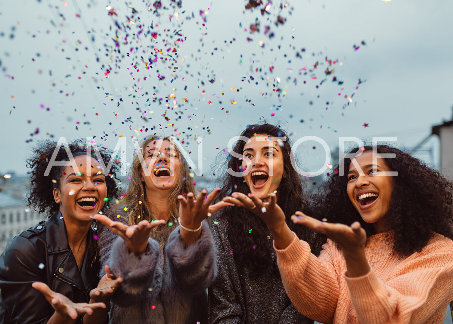 Happy friends standing on a terrace. Group of young women throwing confetti.	