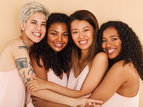 Four smiling diverse women embracing each other. Group of happy females of different races.