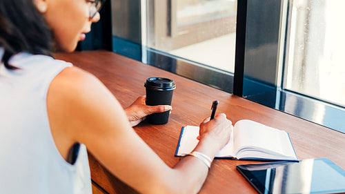 Young entrepreneur taking notes in cafe