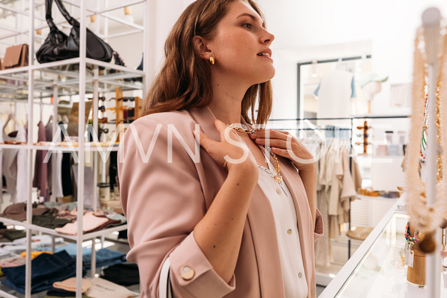 Side view of stylish woman try on a necklace in a small fashion 