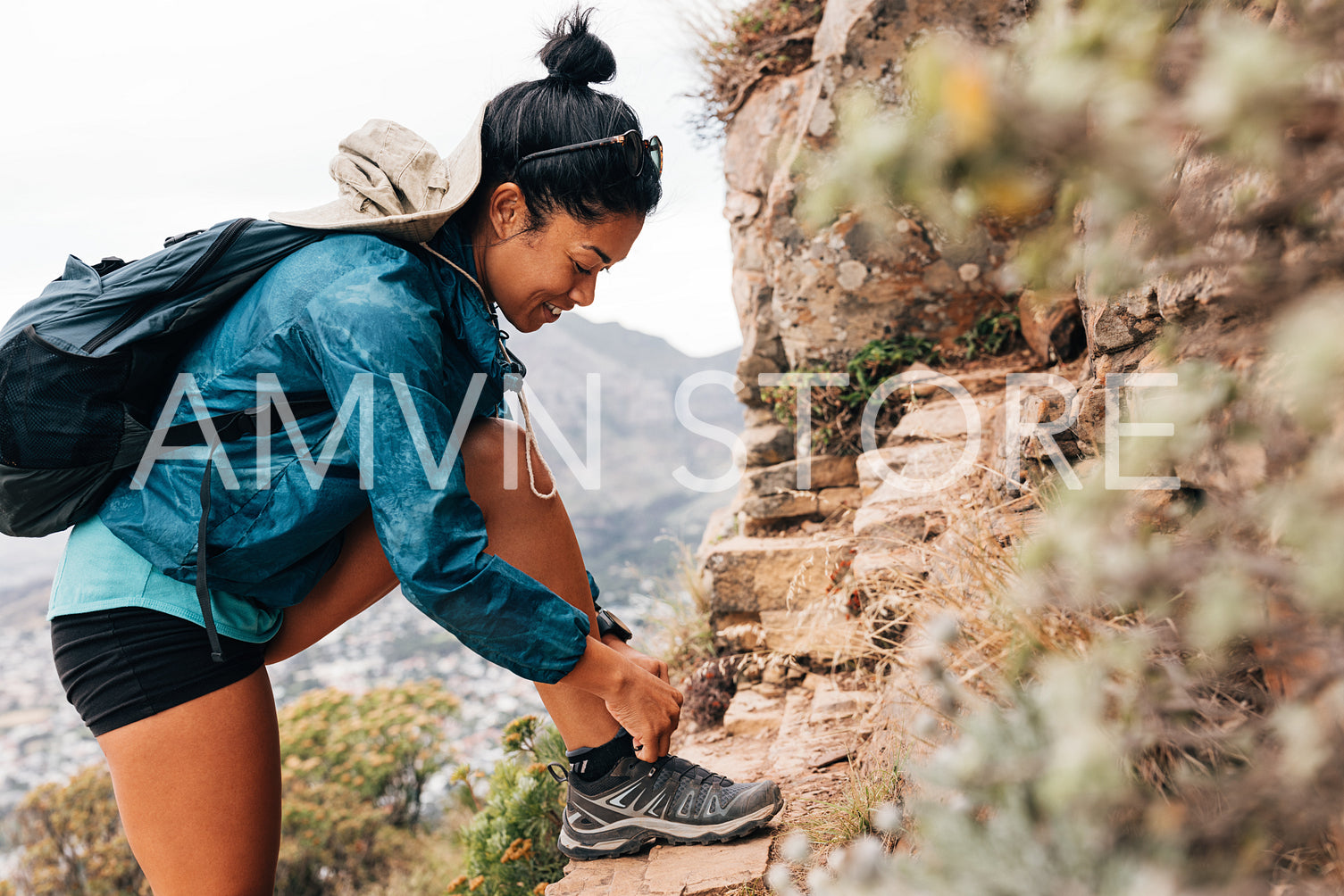 Side view of young woman tying her shoelaces during hike