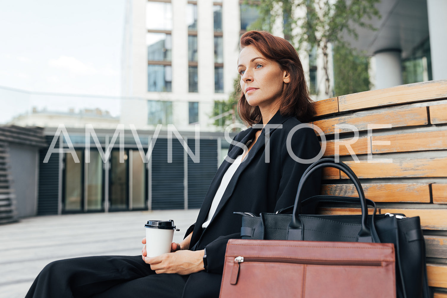 Side view of middle-aged businesswoman sitting outdoors holding a coffee