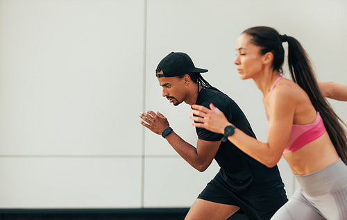 Two athletes prepare to run. Male and female sprinters are running outdoors.