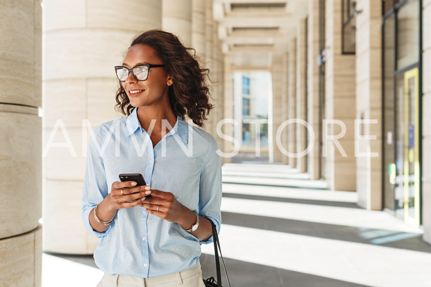 Smiling woman holding a cell phone with office building on background	