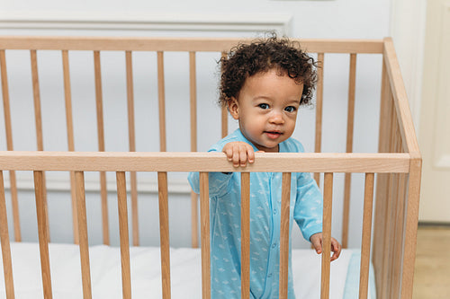 Toddler looking over the railing of his crib