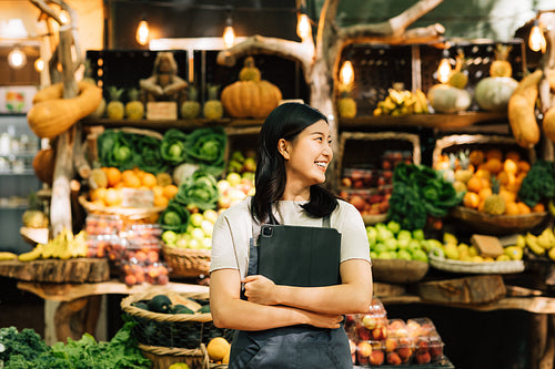 Smiling businesswoman standing at an outdoor market. Female vendor in apron holding digital tablet.