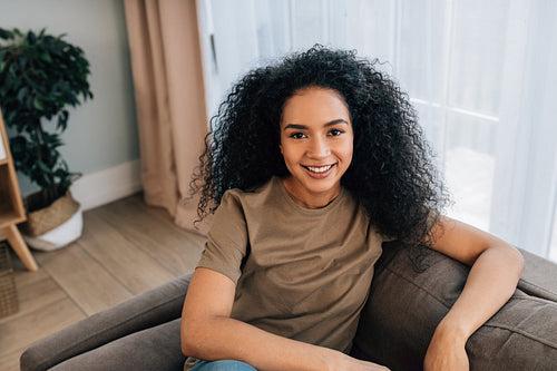 Portrait of a young woman with curly hair sitting on a sofa