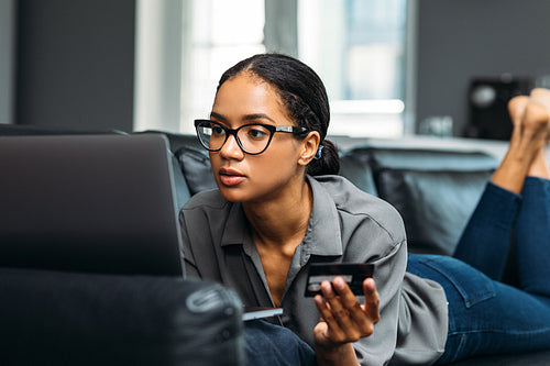 Woman in spectacles holding a credit card and making online payment