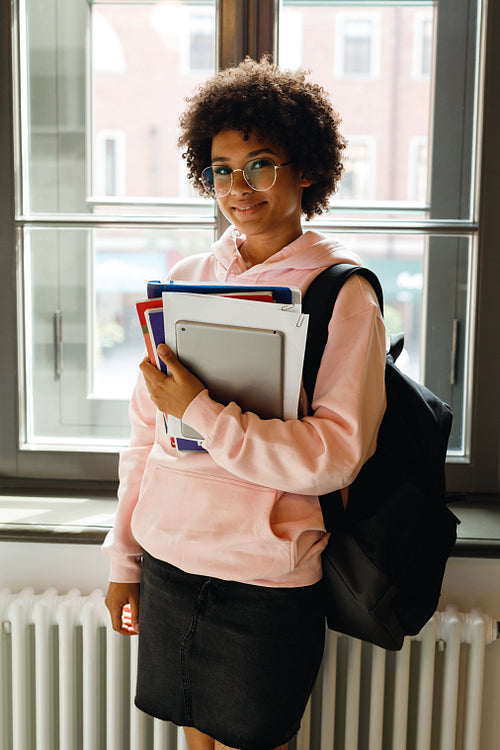 Young smiling student standing at a window, preparing for lecture