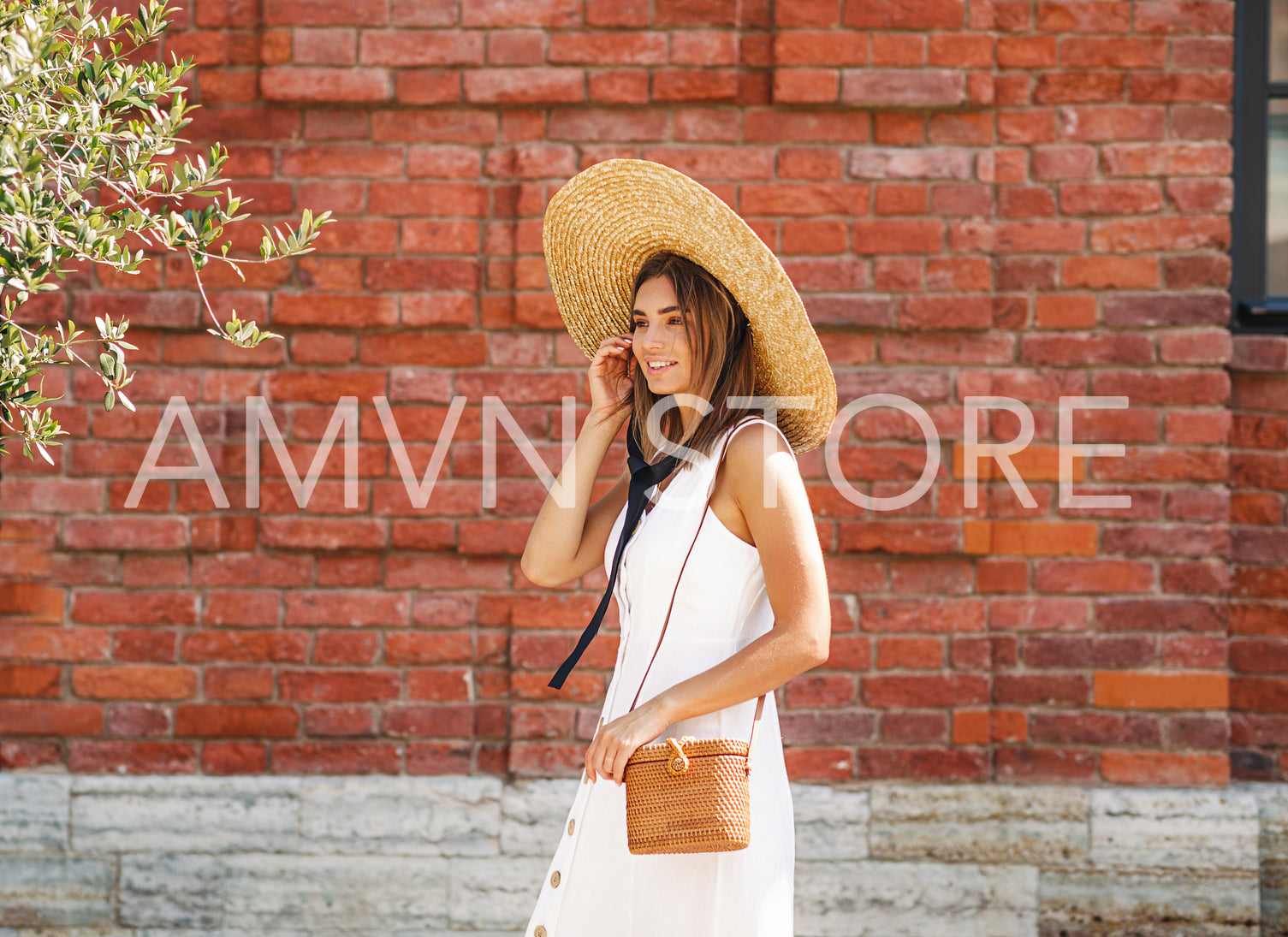 Side view of a young stylish woman in a big hat walking on the city street	