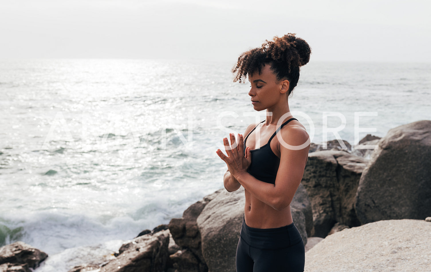 Side view of slim woman with folded hands meditating with closed eyes outdoors