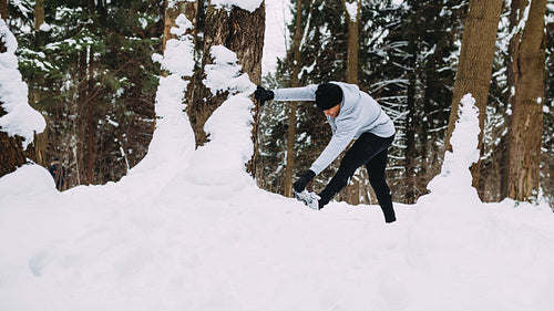 Runner doing stretching exercises in a winter park, warming up before training