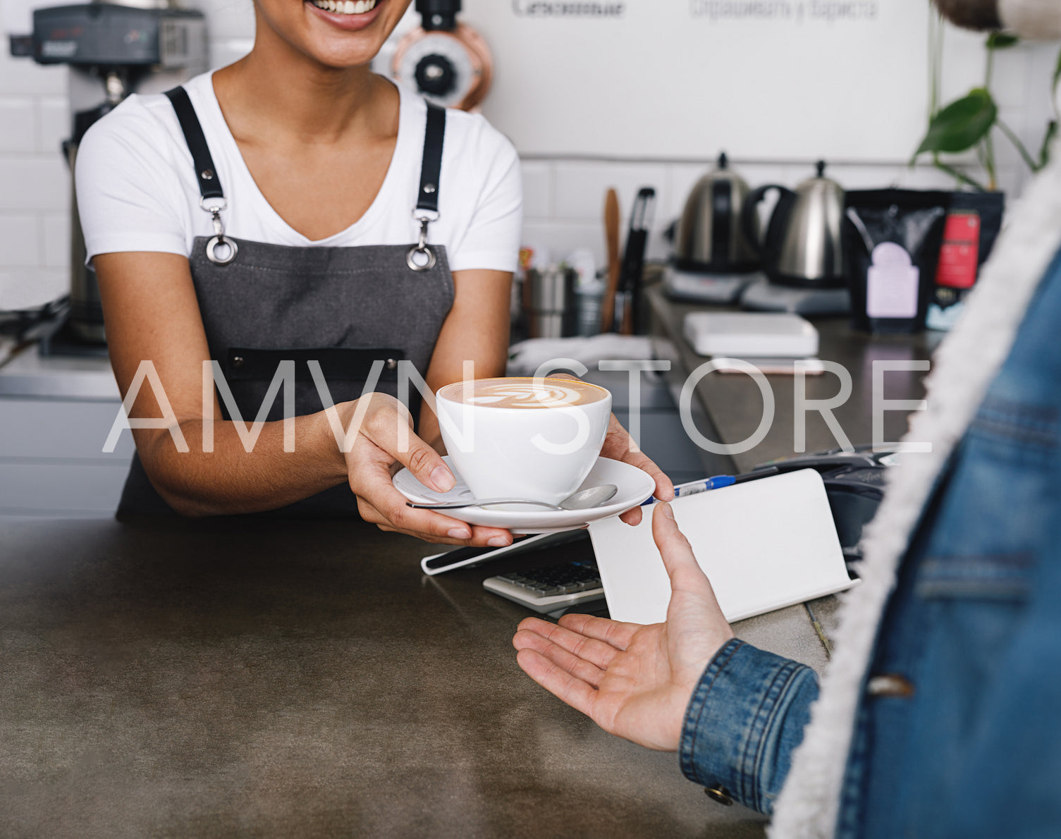 Unrecognizable coffee shop owner handing over a cup of coffee to her customer	