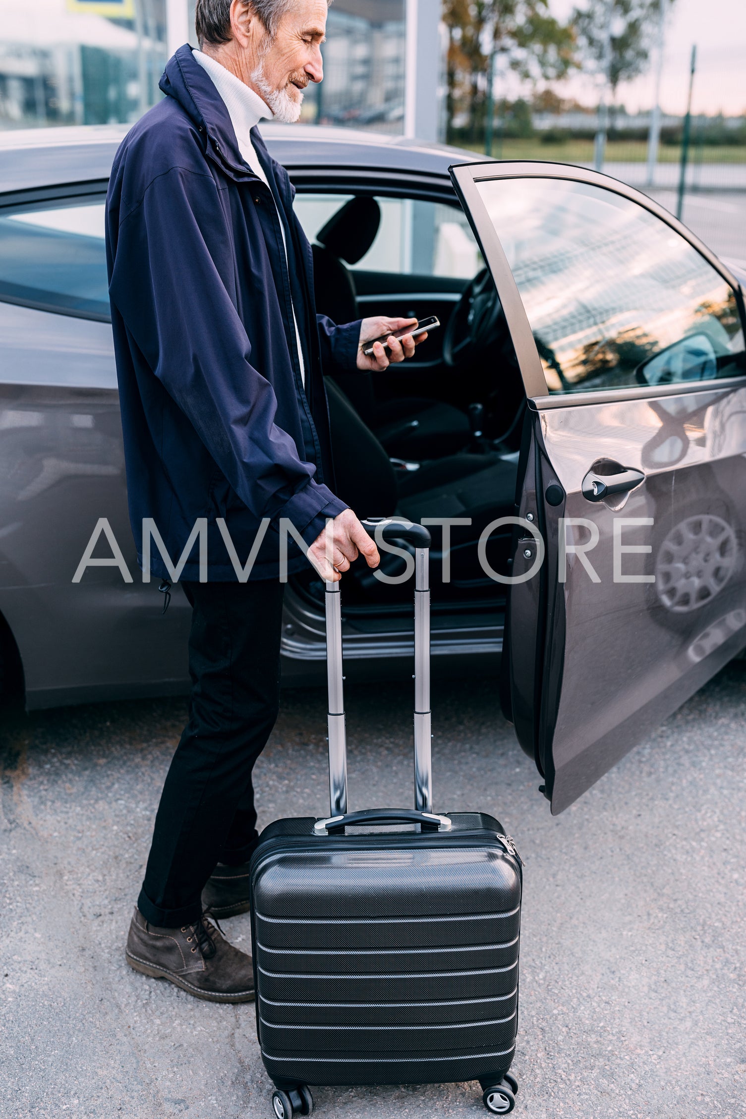 Side view of a mature tourist standing near the car and looking on cell phone	