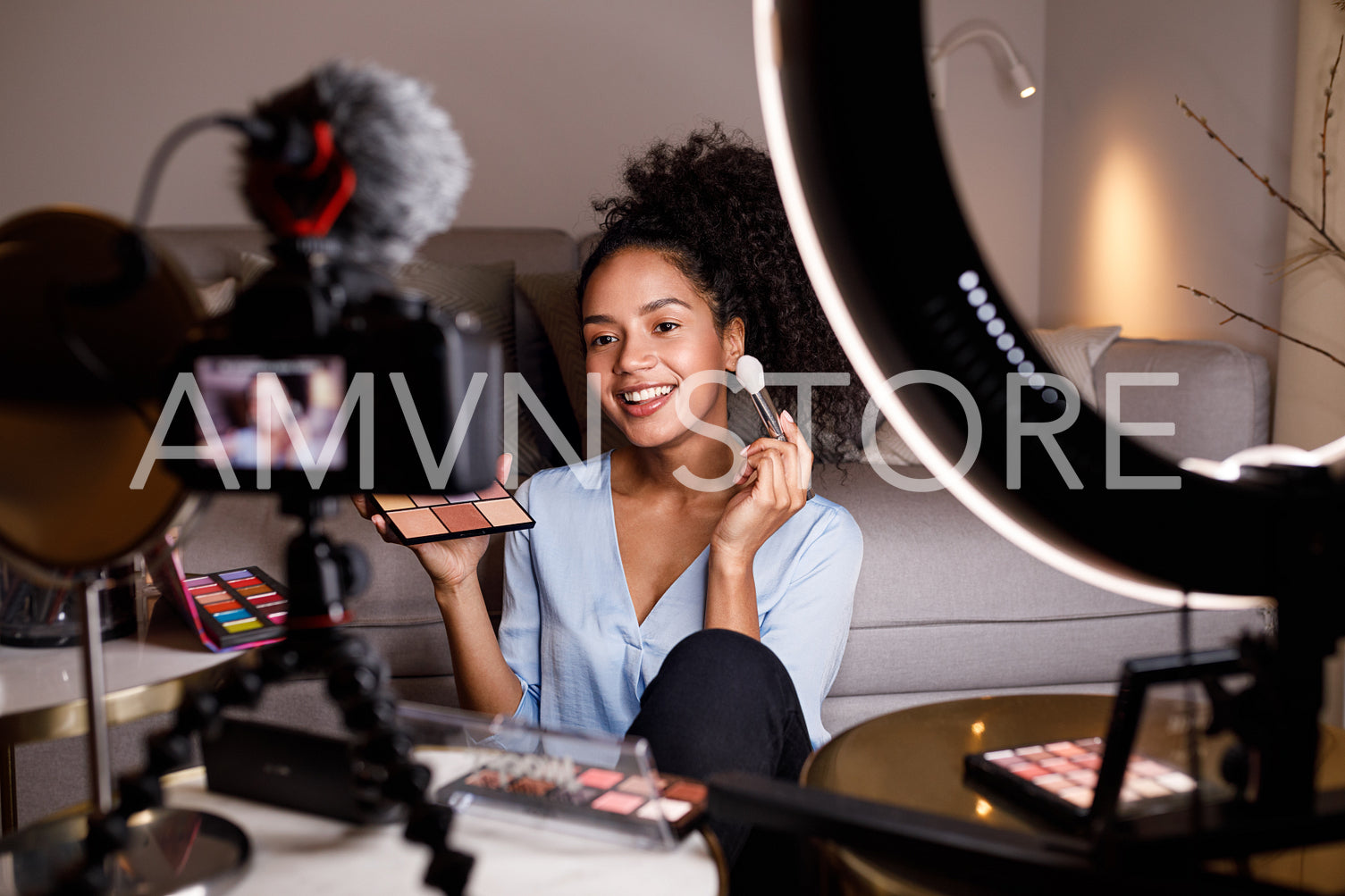 Beauty vlogger making a video tutorial on makeup in living room	