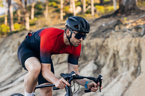 Professional male cyclist riding a bike outdoors. Cyclist in a sports outfit practicing on a road bike.