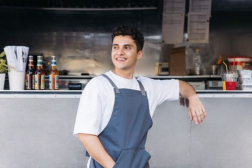 Portrait of a young waiter standing at a food truck and looking away