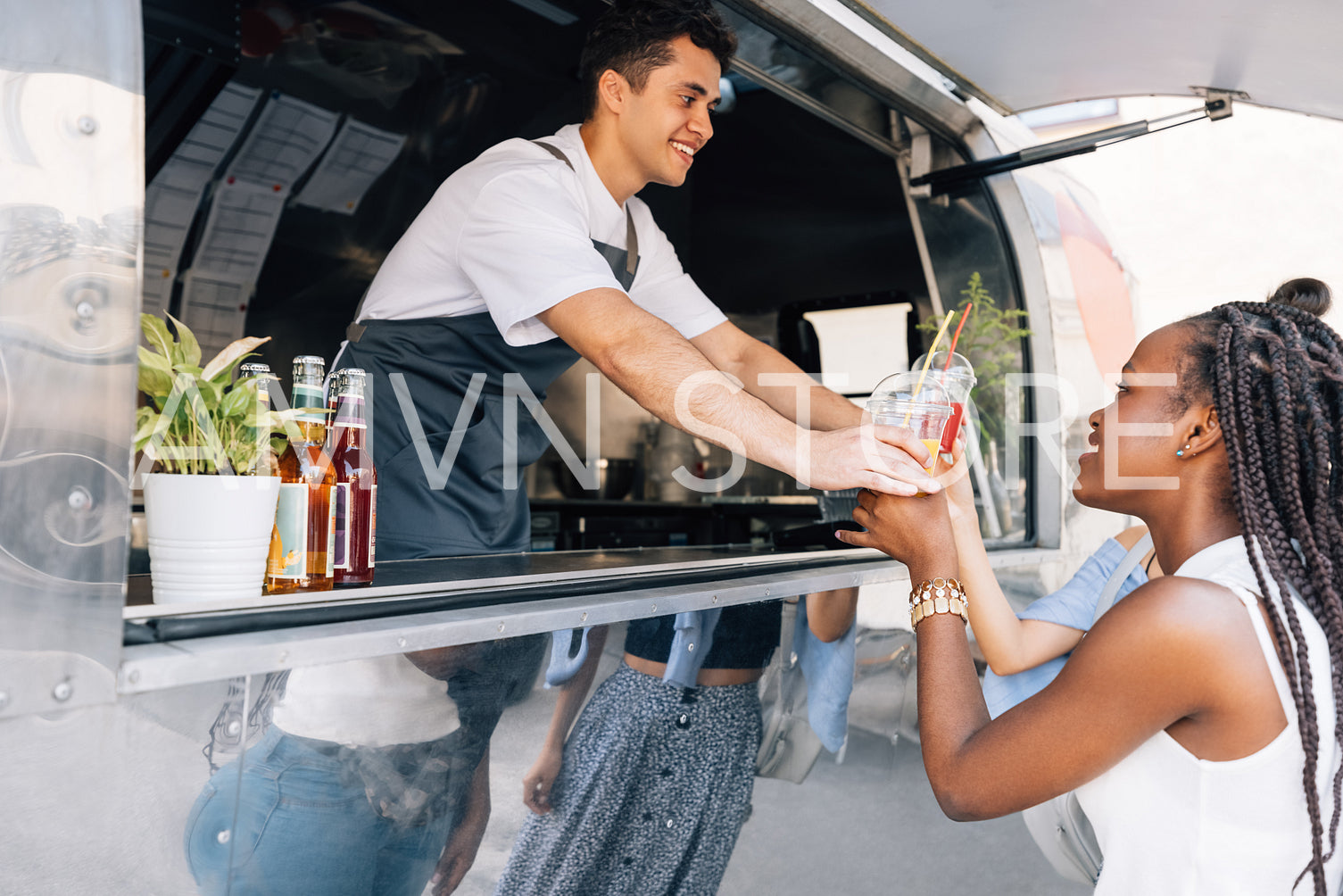 Side view of women buying drinks from a male owner at a food truck