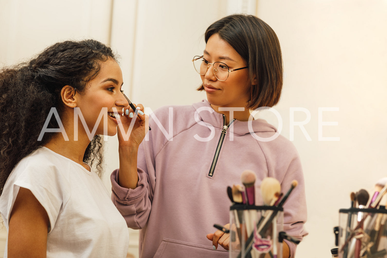 Makeup artist applying makeover on a model face in dressing room	
