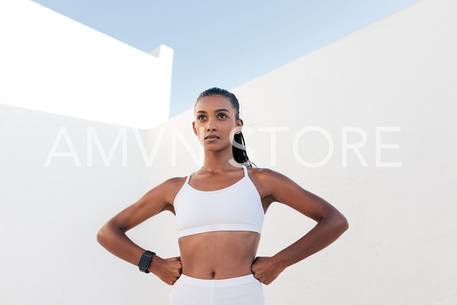 Confident female athlete in white sport clothes with hands on hips