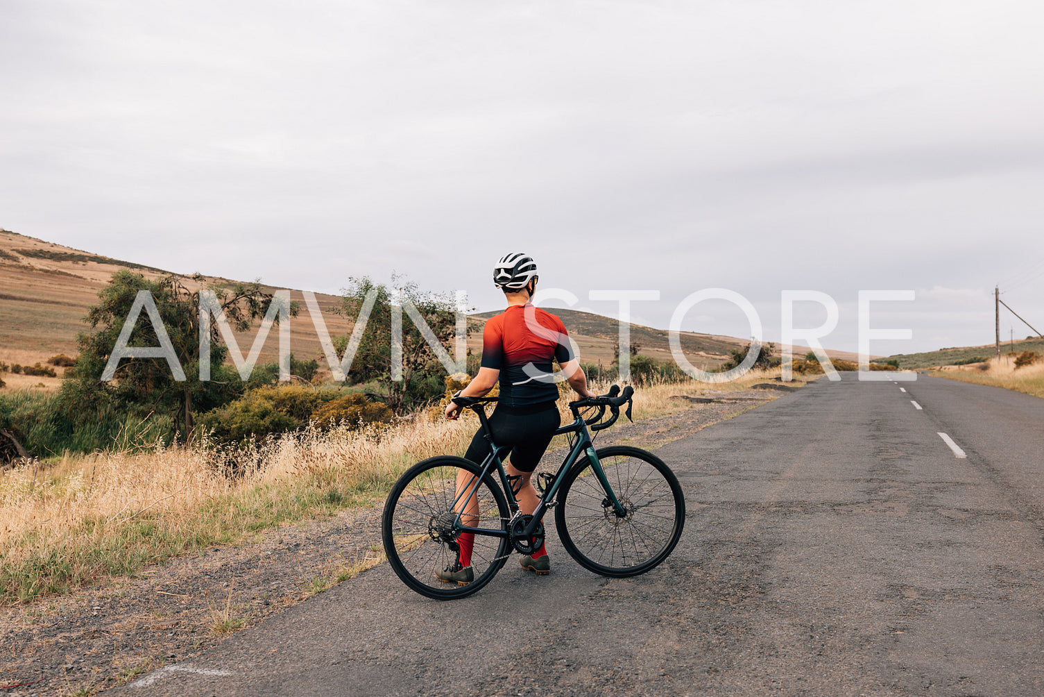 Rear view of professional woman cyclist sitting on her road bike relaxing after training