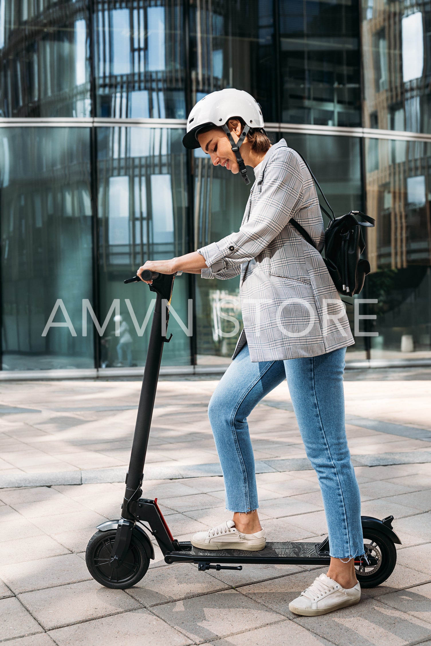 Young caucasian woman wearing cycling helmet standing outdoors with electric push scooter near glass building