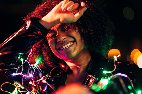 Happy woman posing at night with colored and christmas lights