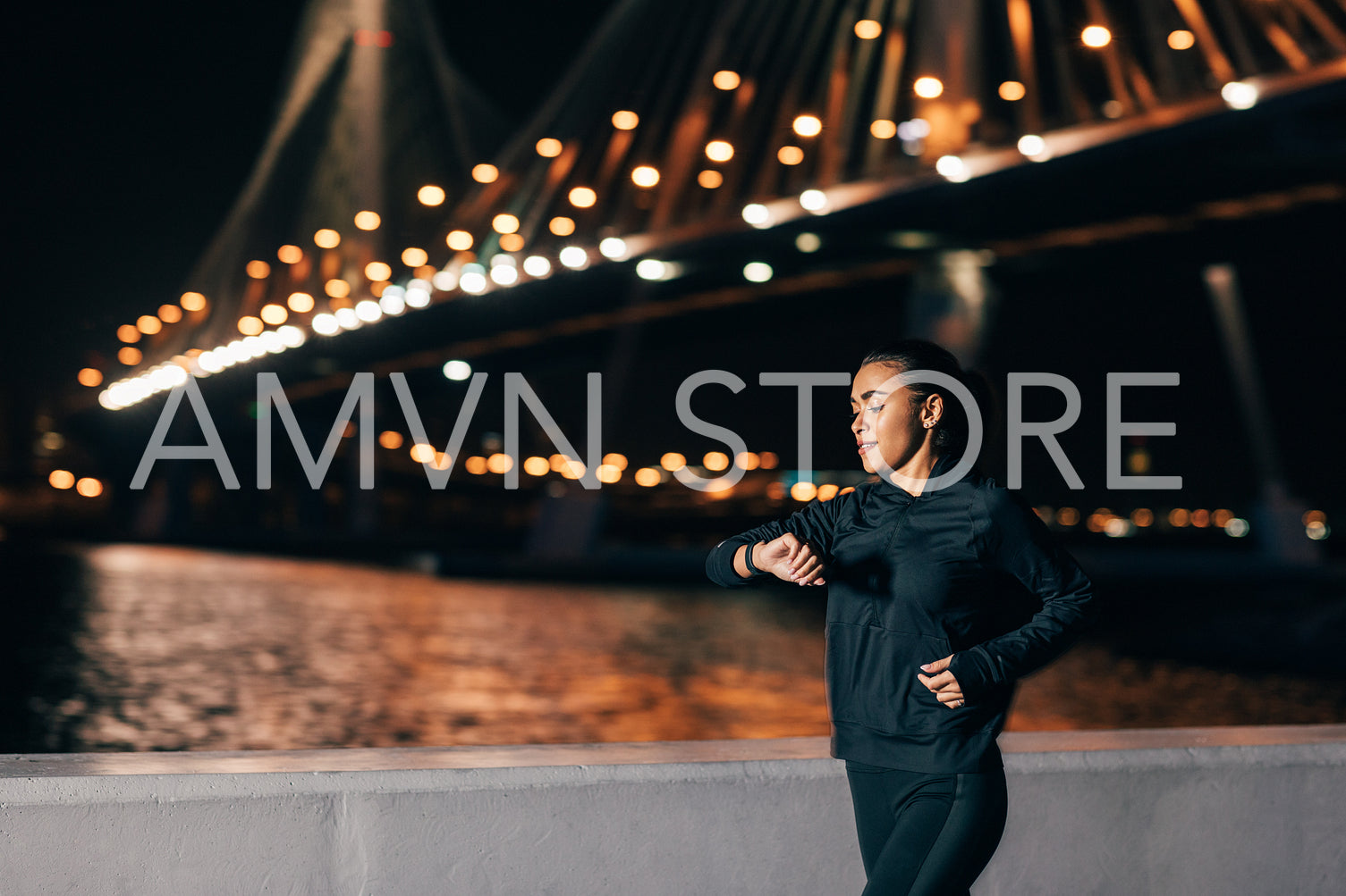 Young fit woman in sport clothes looking at smartwatch while jogging on an embankment at night