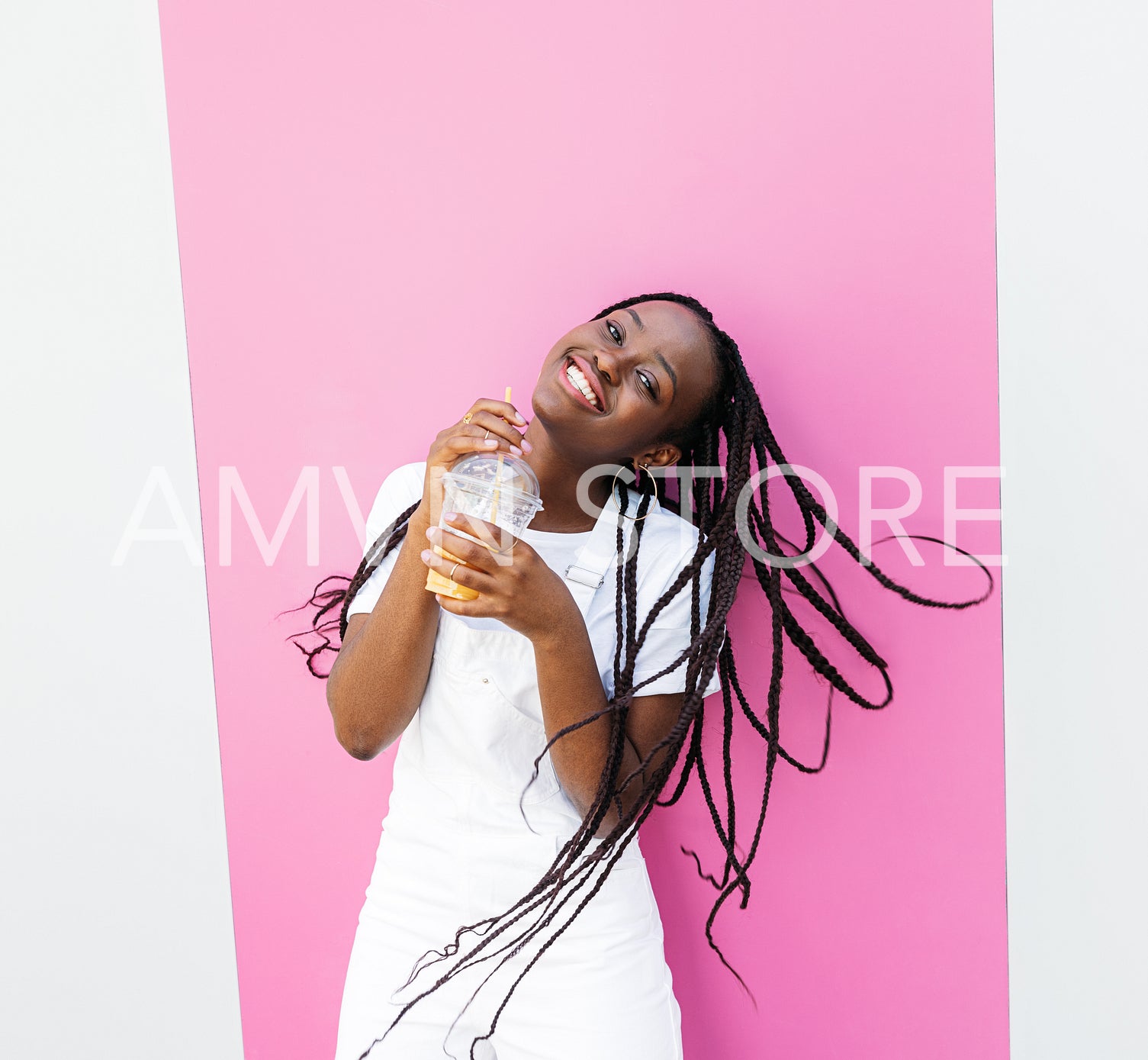 Happy girl with juice standing at the pink stripe and looking at camera